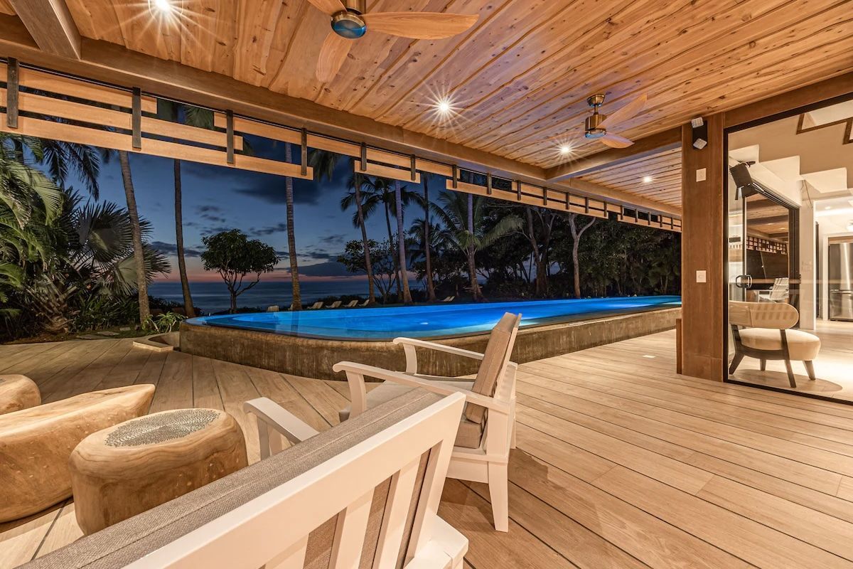 Terrasse extérieure avec piscine et vue sur l'océan au crépuscule.