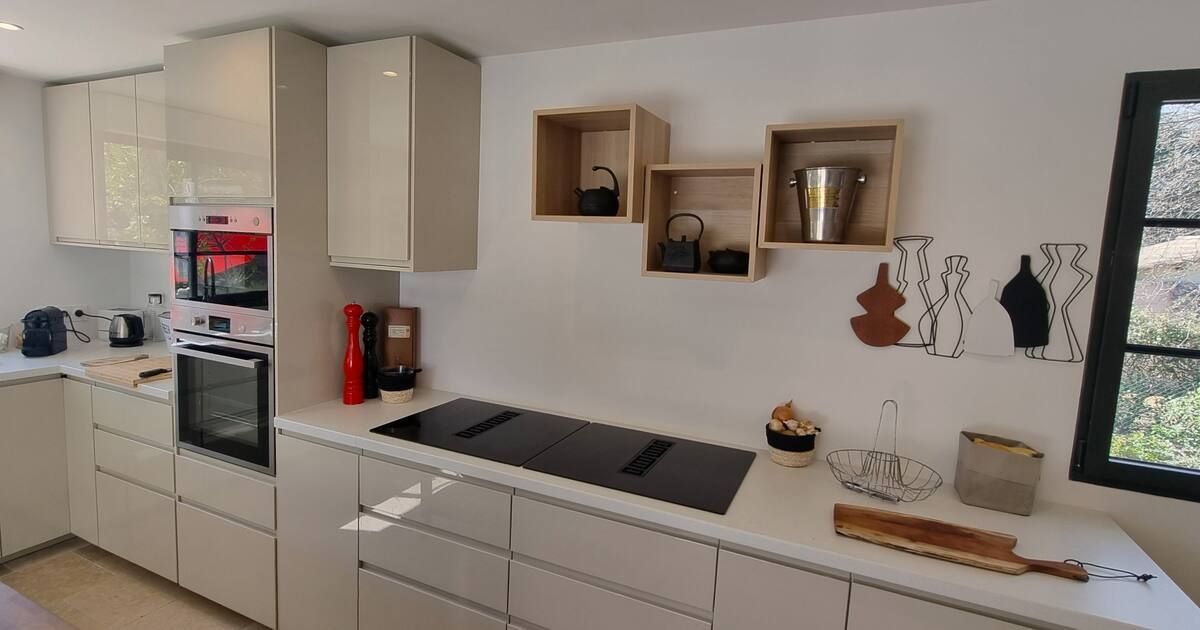 Cuisine moderne avec armoires blanches, cuisinière et étagères flottantes.