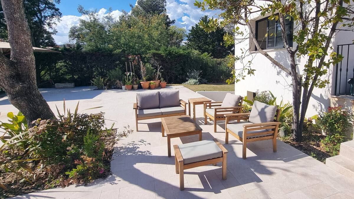 Terrasse extérieure avec mobilier en bois : canapé, chaises et tables.