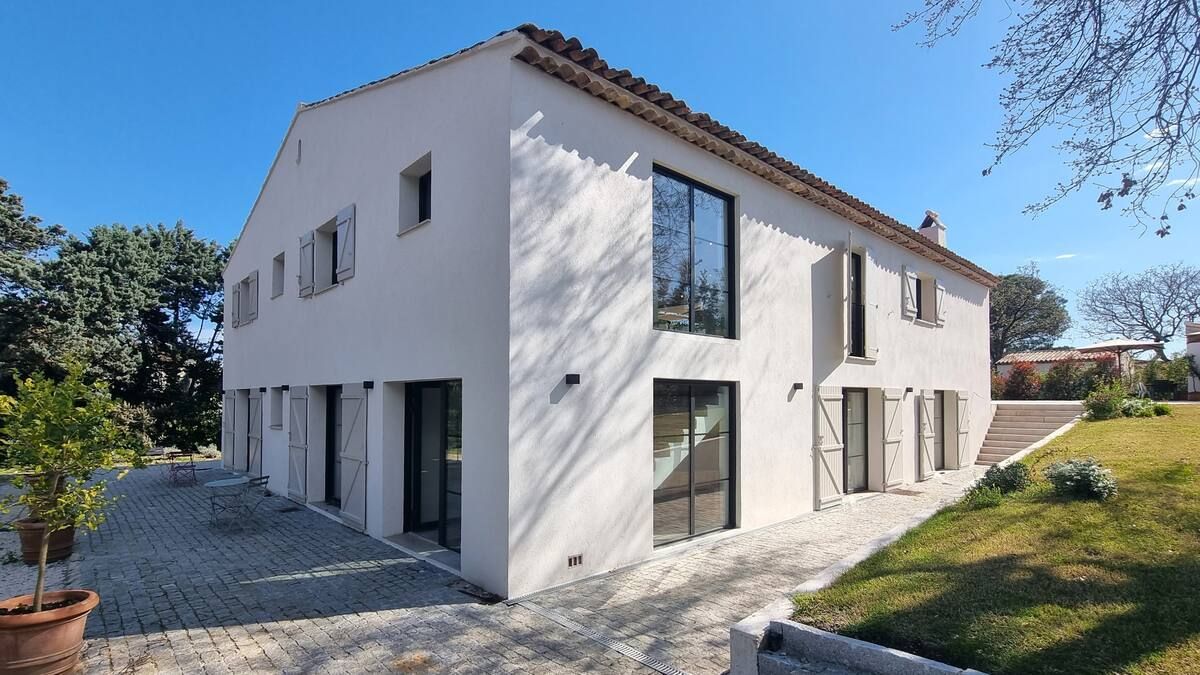 Maison blanche à deux étages avec des cadres de fenêtres sombres, des volets