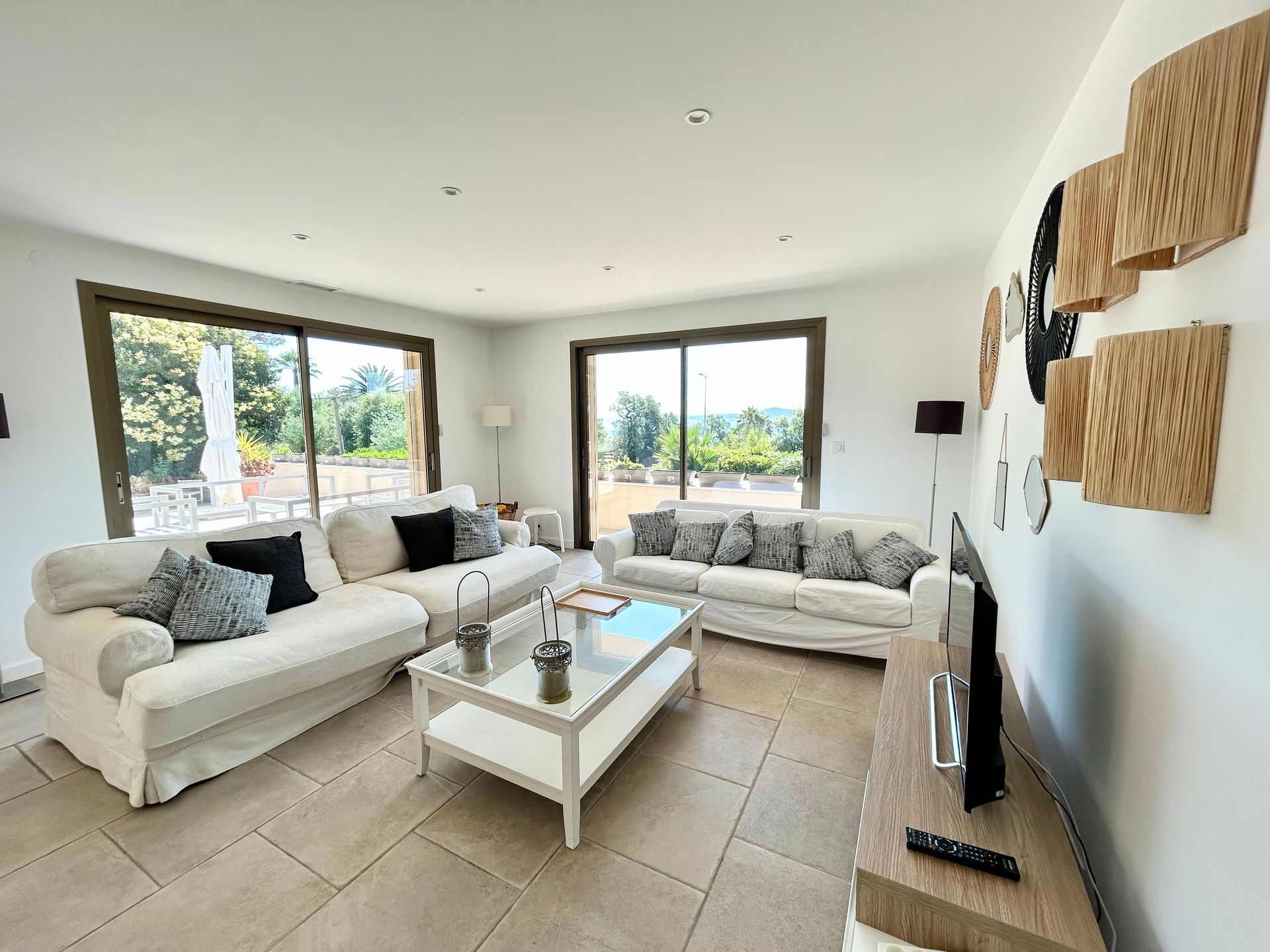 Salon spacieux et blanc avec canapés, table basse et grandes fenêtres donnant sur une vue panoramique.