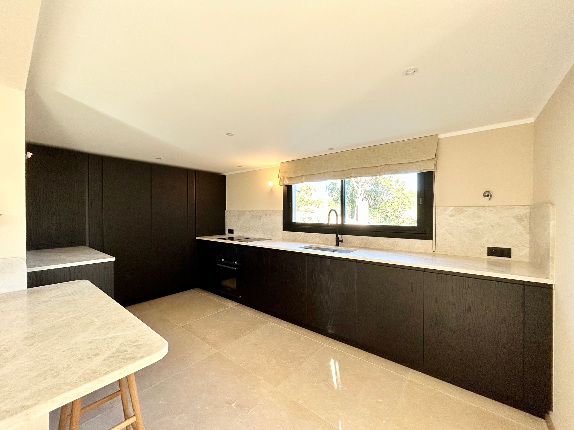 Cuisine moderne avec armoires foncées, comptoirs clairs et une fenêtre.