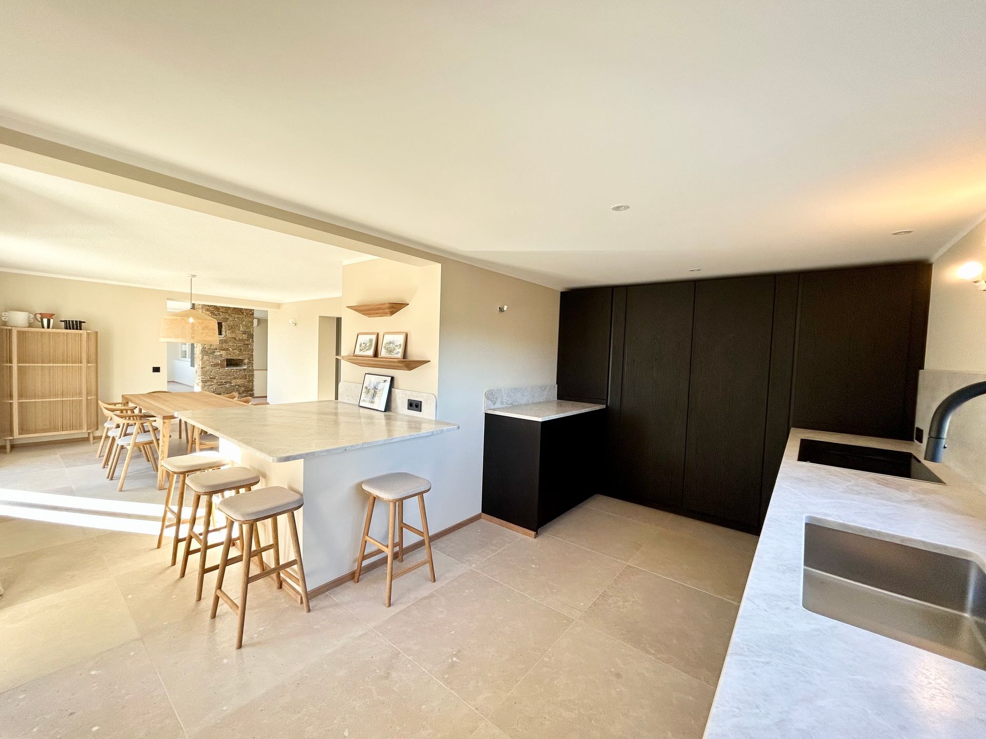 Cuisine moderne avec îlot et tabourets, armoires foncées et comptoirs en pierre.