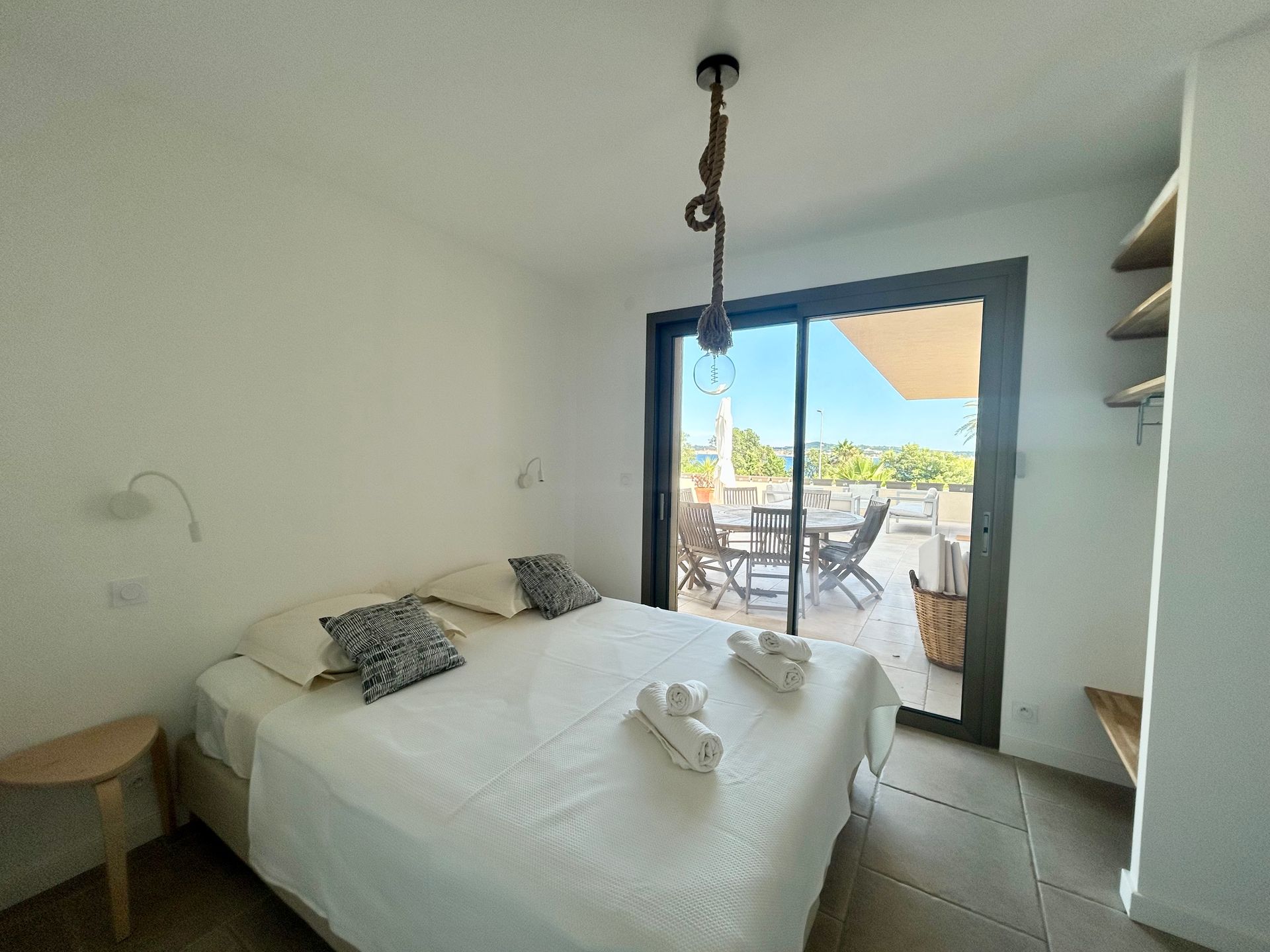 Chambre avec un lit, une porte coulissante donnant sur un patio et un luminaire suspendu.