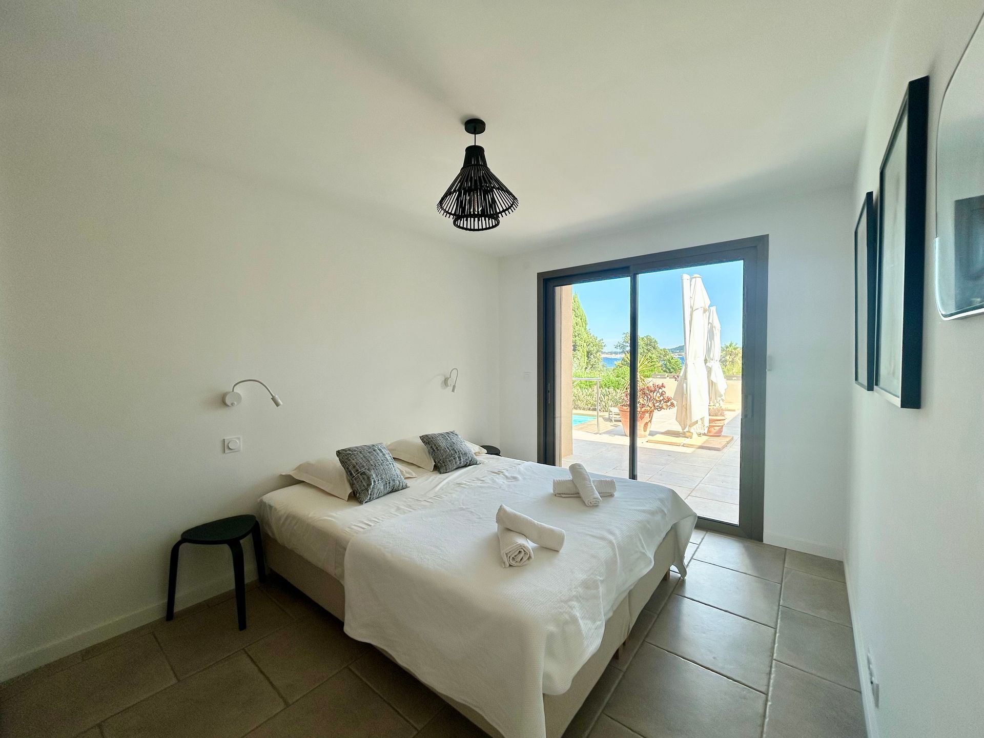 Chambre avec un lit double, des portes coulissantes en verre et un luminaire suspendu noir.