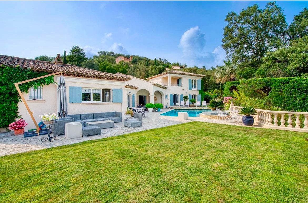 Maison avec piscine ; panneau « VENDU » (vendu). Piscine bleue, terrasse beige, arbres verts, volets bleu clair.