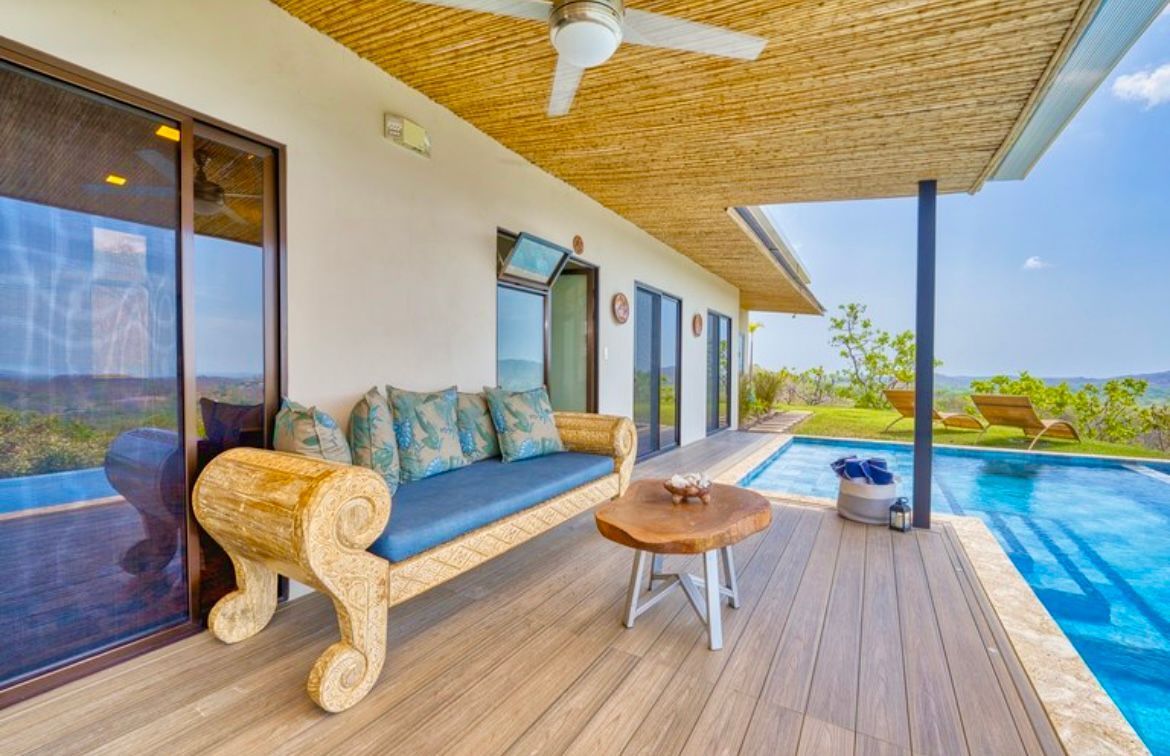 Terrasse extérieure avec canapé, piscine et vue sur l'océan.