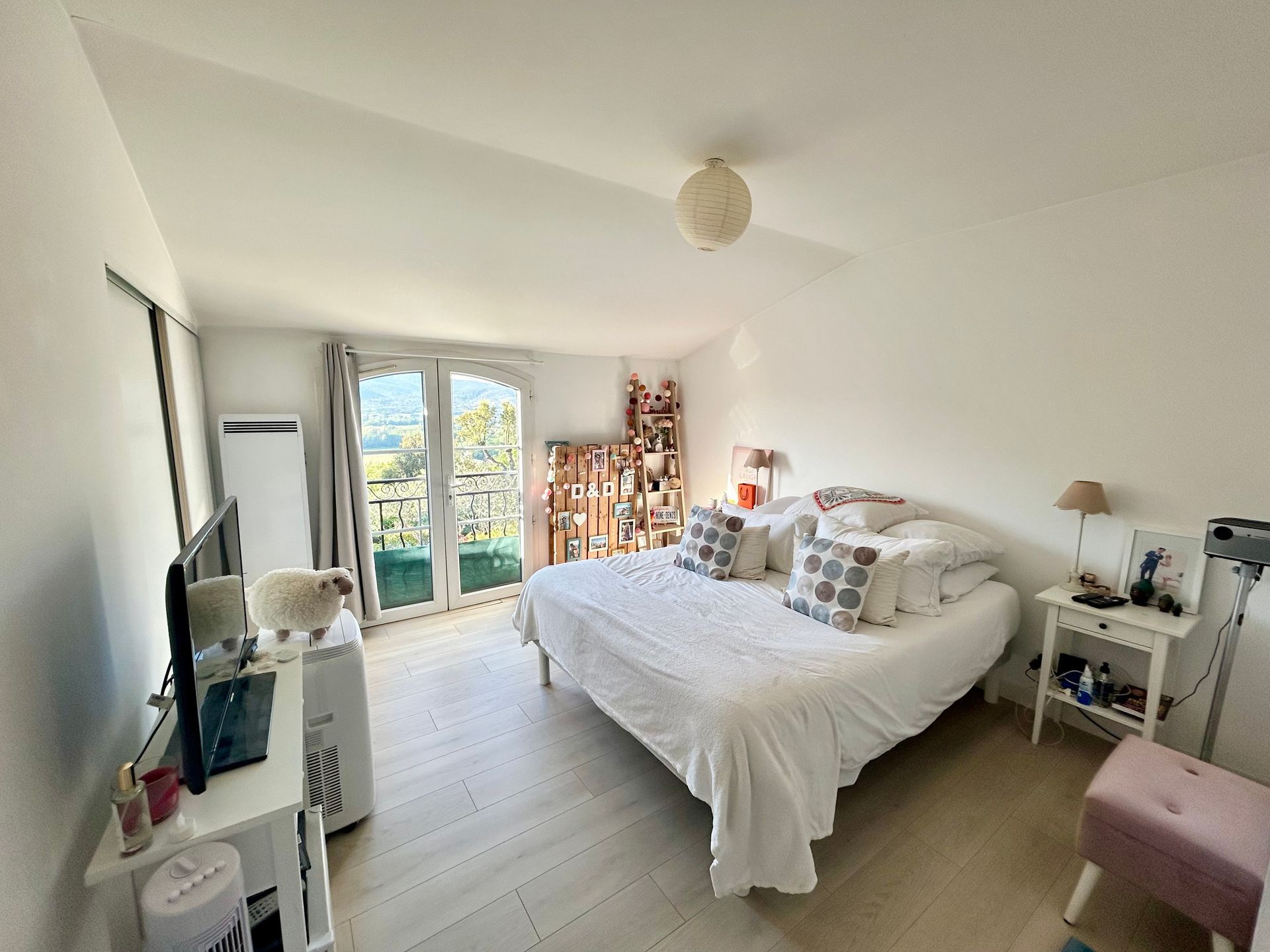 Chambre avec un lit, de petites tables de chevet et un balcon avec vue.