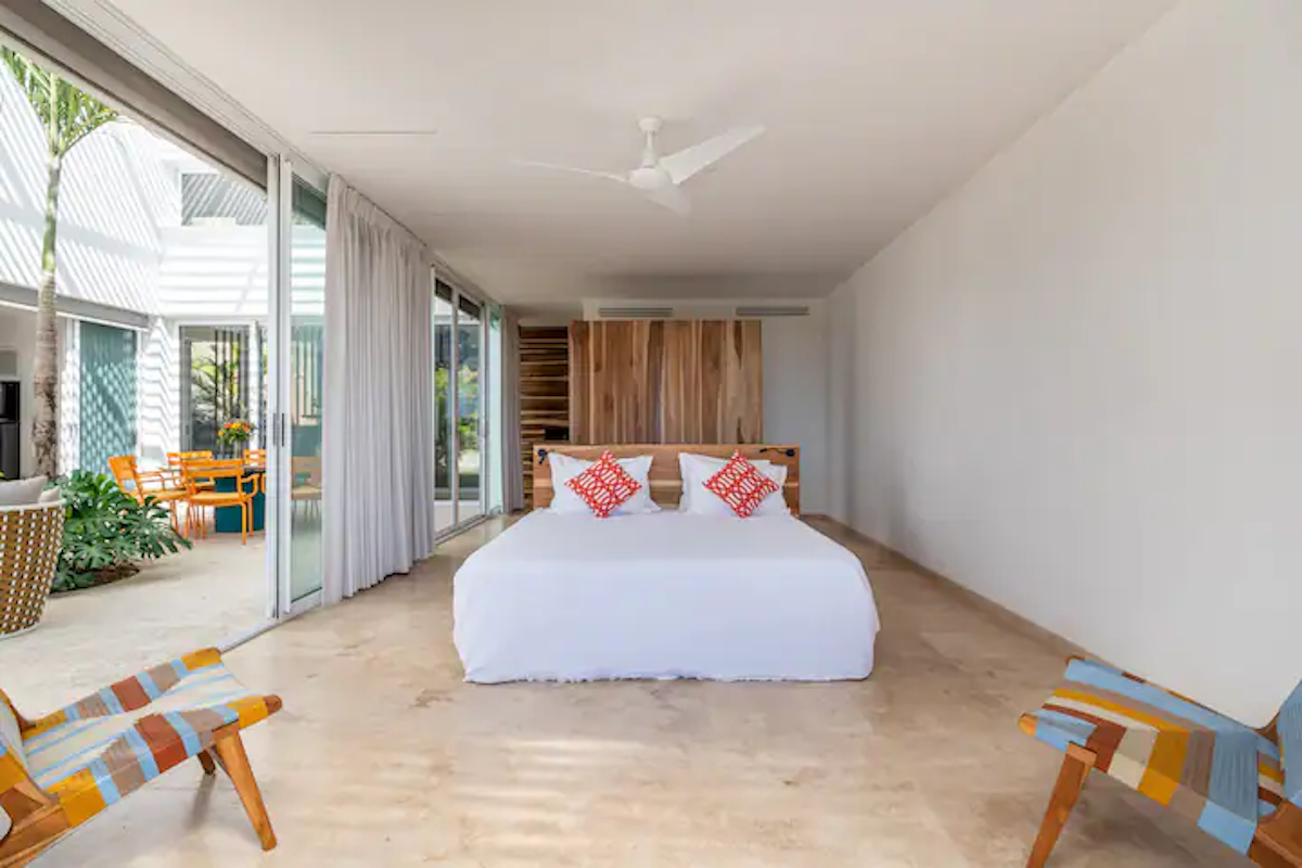 Chambre avec un lit et deux chaises, ouvrant sur un patio avec une table et des chaises.