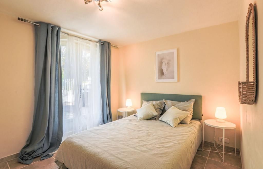 Chambre avec lit, tables de chevet, fenêtre avec rideaux et œuvres d'art au mur.