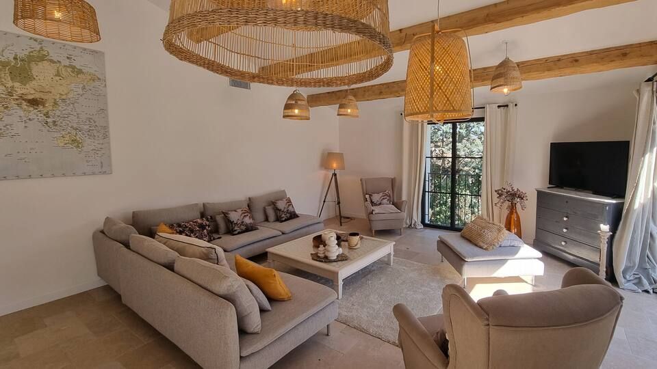 Salon aux tons neutres, luminaires et un grand canapé, avec un tableau au mur et une fenêtre.