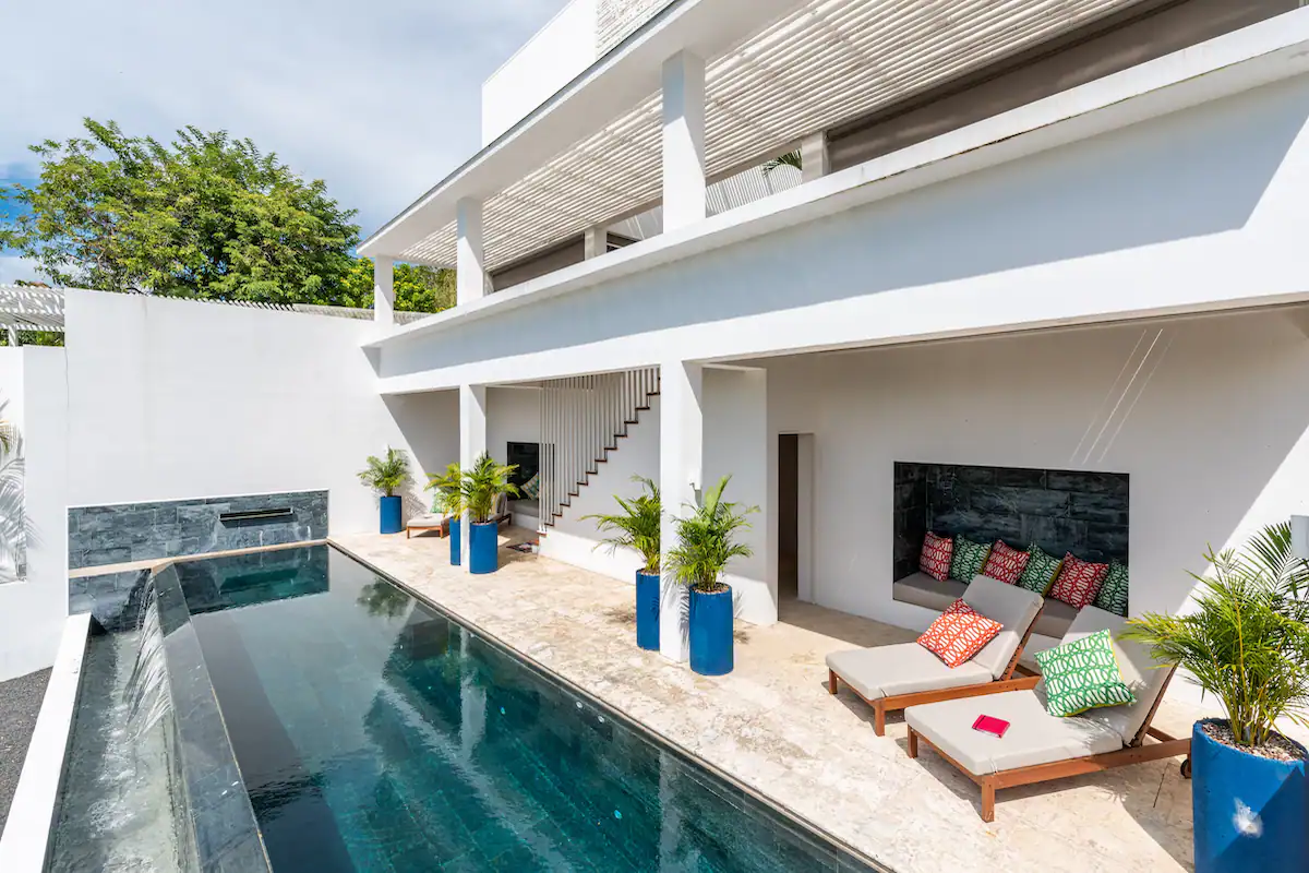 Vue sur la piscine avec piscine, chaises longues et architecture moderne blanche.