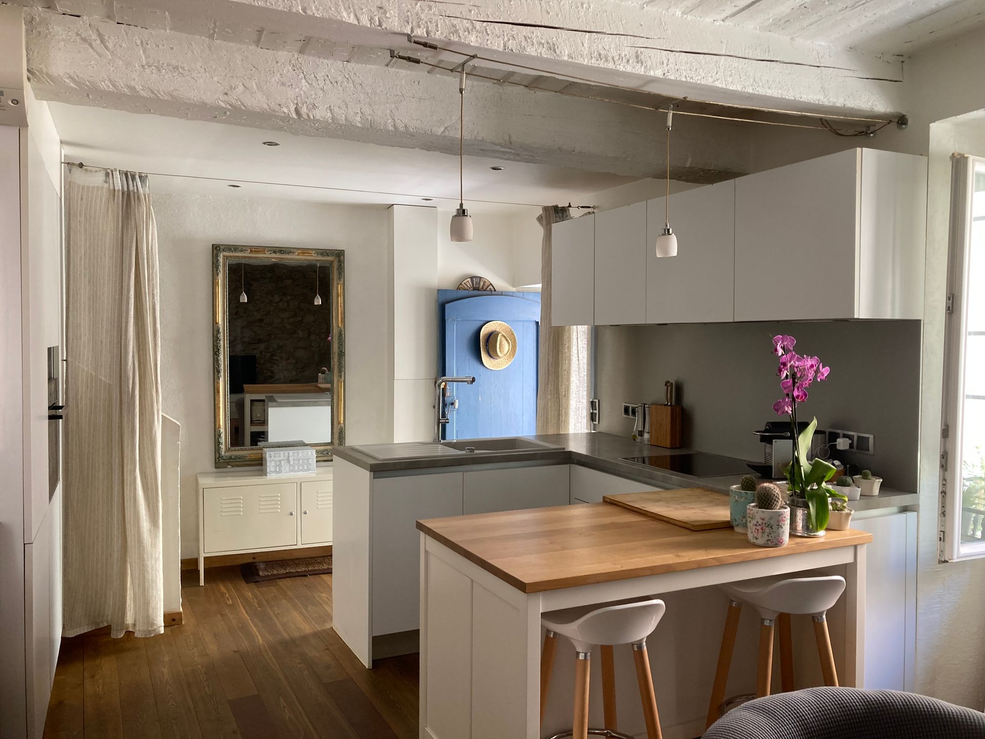 Cuisine chaleureuse avec armoires blanches, îlot en bois et réfrigérateur rétro bleu.