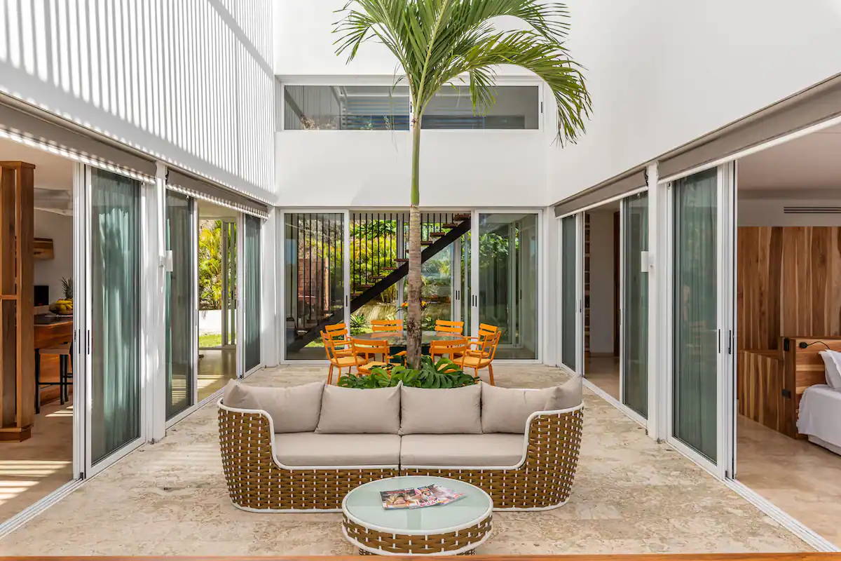 Espace de vie extérieur avec canapé en osier, table basse ronde et coin repas.