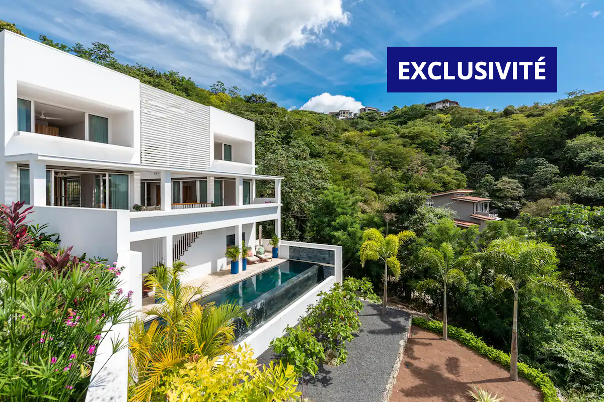 Villa blanche moderne avec piscine à débordement dans un cadre tropical luxuriant ; Label