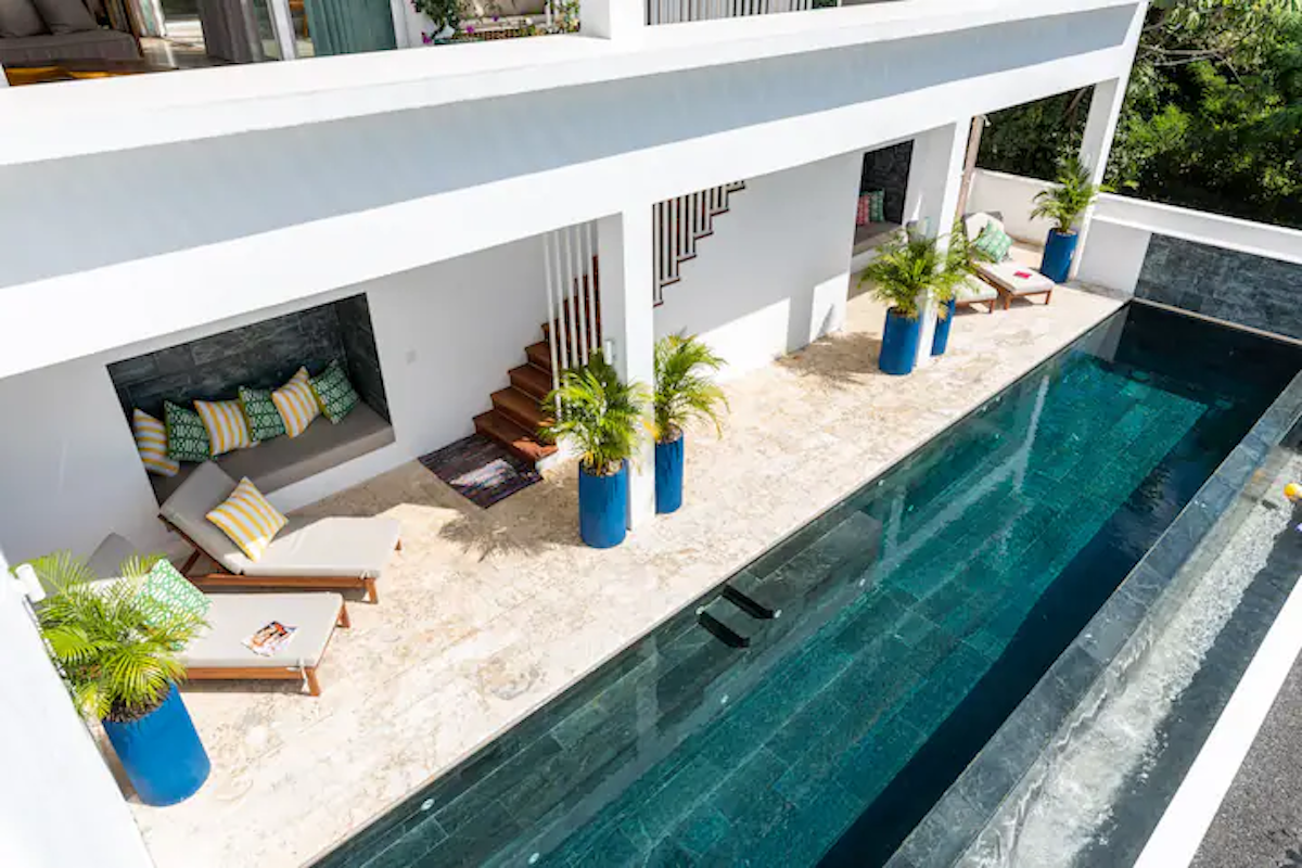 Bâtiment blanc moderne avec piscine. Espace détente, escalier, jardinières bleues, eau de piscine sombre