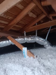 An attic with a lot of insulation and pipes