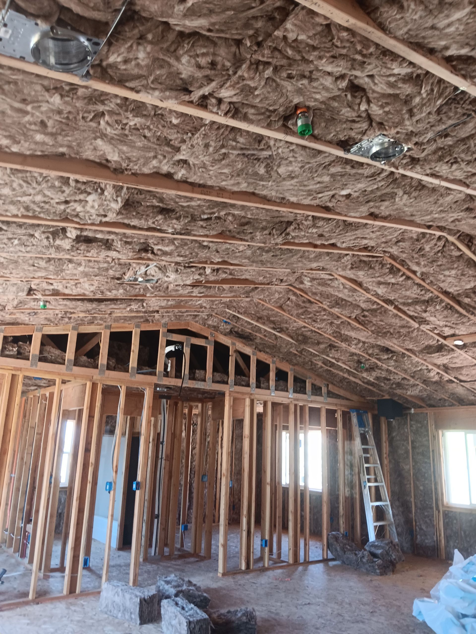 A room with a ladder and a lot of insulation on the ceiling.