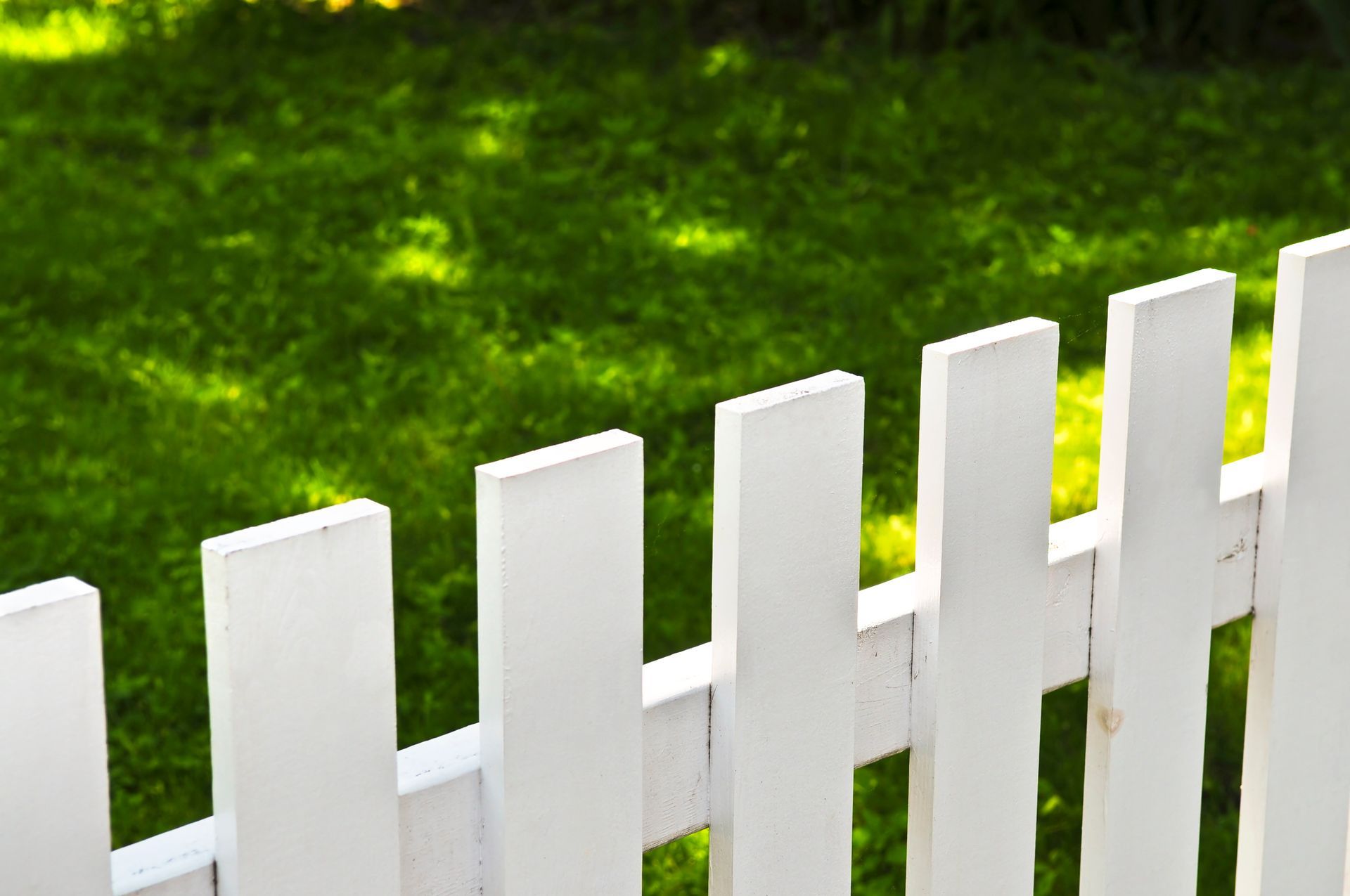A white picket fence surrounds a lush green yard.
