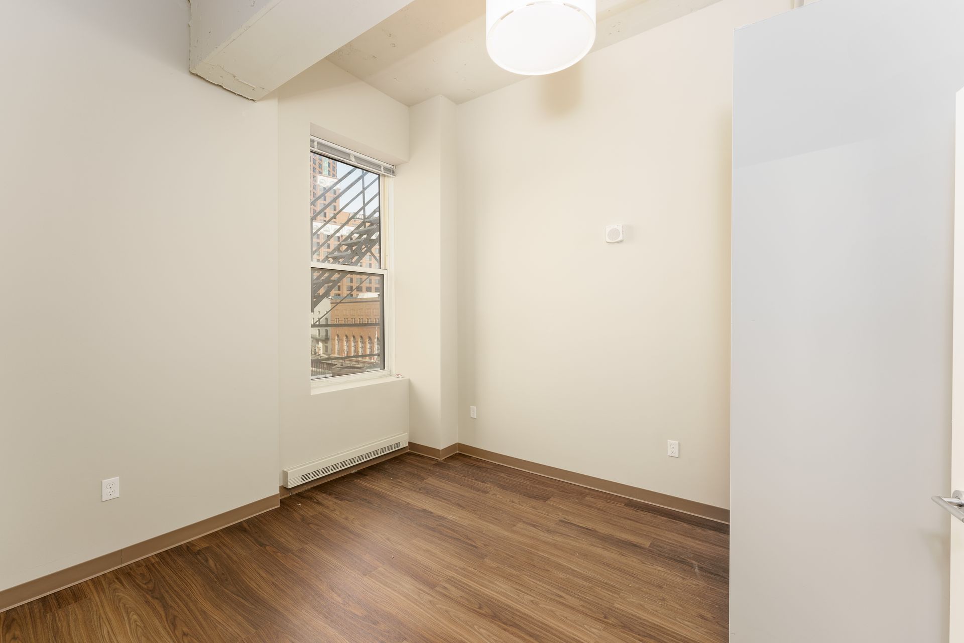 An empty room with hardwood floors and a window.