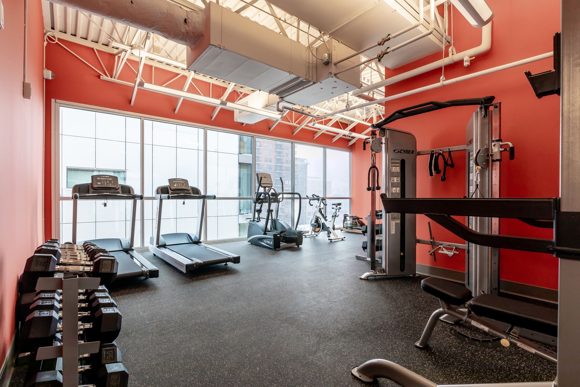 A gym with treadmills and dumbbells in it