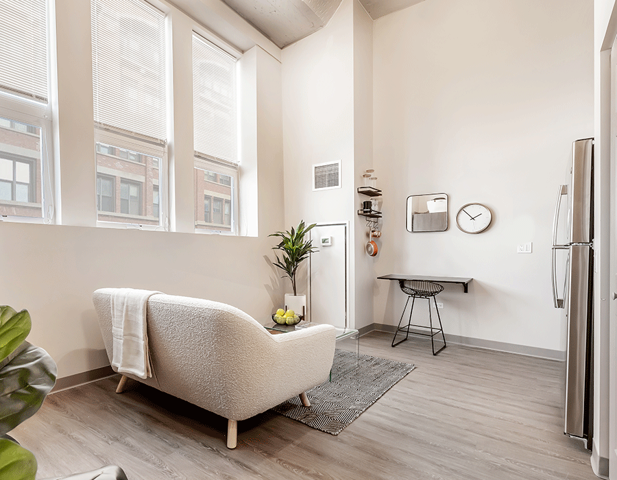 A living room with a couch , desk and refrigerator.