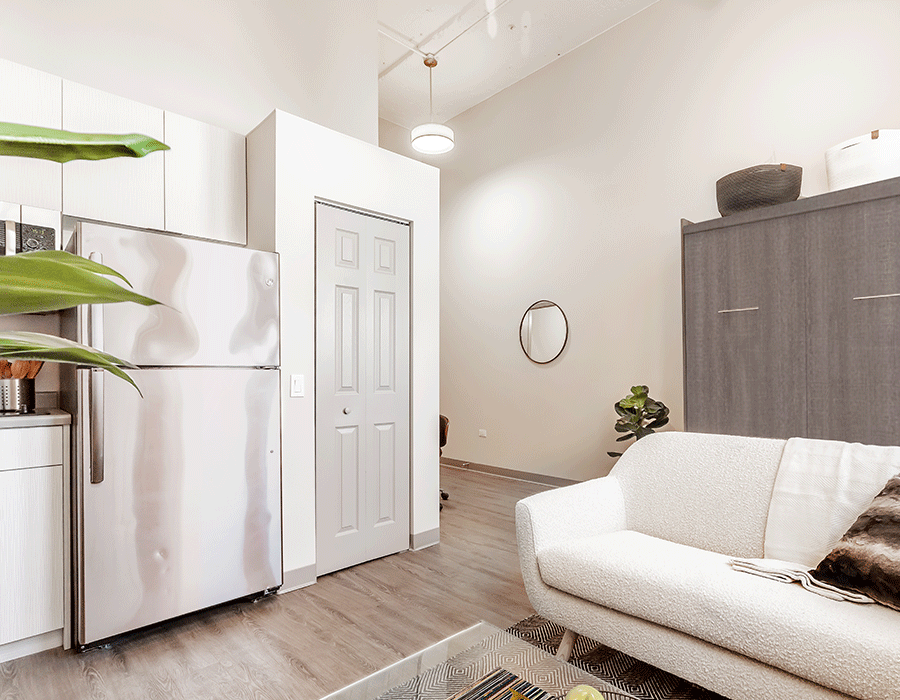A living room with a couch , refrigerator , and microwave.