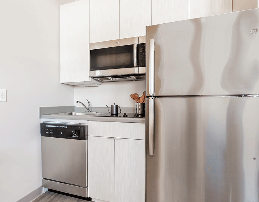 A kitchen with a stainless steel refrigerator , dishwasher , and microwave.