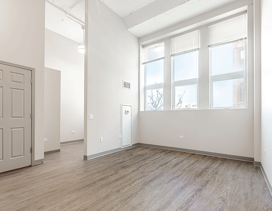 An empty room with hardwood floors and a large window.