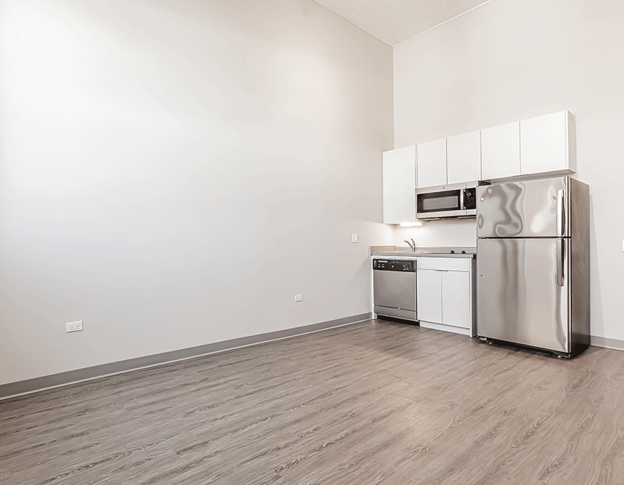 An empty kitchen with stainless steel appliances and white cabinets.