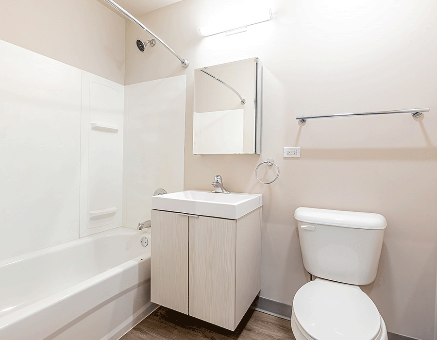 A bathroom with a toilet , sink , bathtub and mirror.