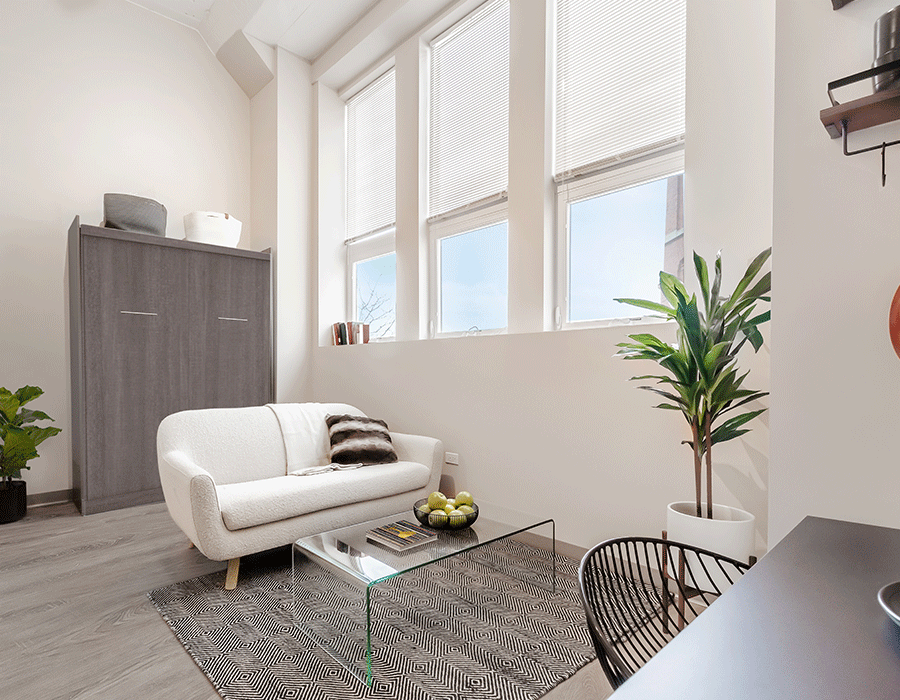 A living room with a white couch and a glass coffee table