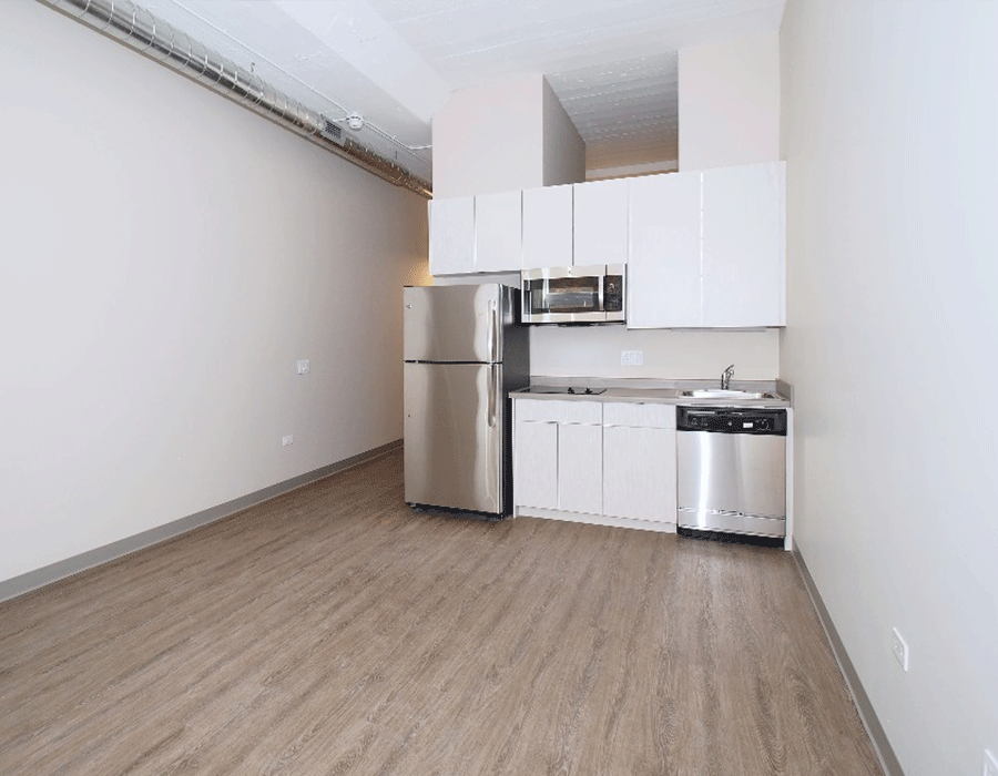 An empty kitchen with stainless steel appliances and white cabinets