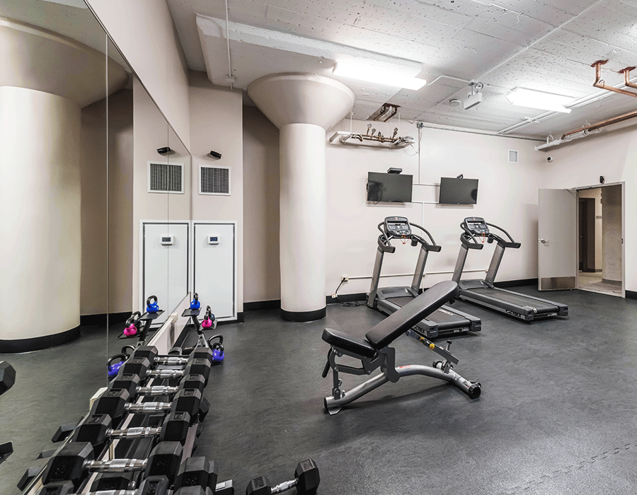 A gym with treadmills , dumbbells and a bench