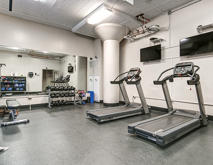 A gym with treadmills , dumbbells and a mirror.