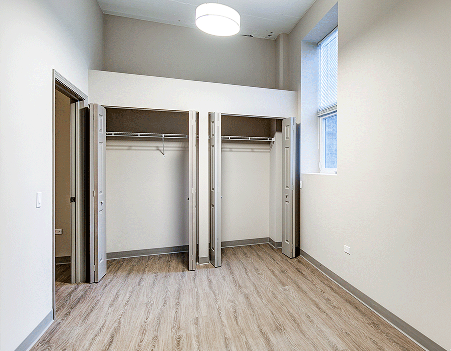 A bedroom with a lot of closets and a window.