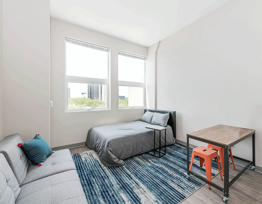 A bedroom with a bed , couch , table and chairs.