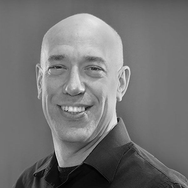 A bald man is smiling in a black and white photo.