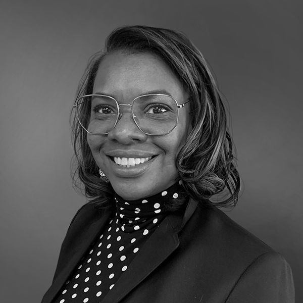 A black and white photo of a woman wearing glasses and a polka dot shirt.