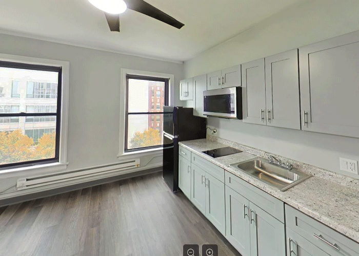 A kitchen with a sink , refrigerator , microwave and ceiling fan.