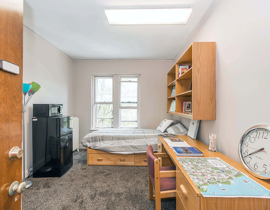 A bedroom with a bed , desk , and clock.