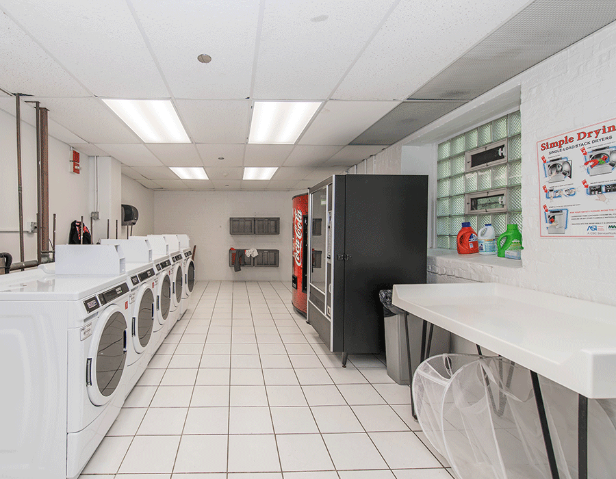 A laundromat with a lot of washing machines and a vending machine.