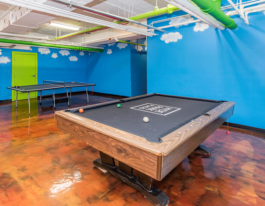 A pool table in a room with blue walls and ping pong tables.