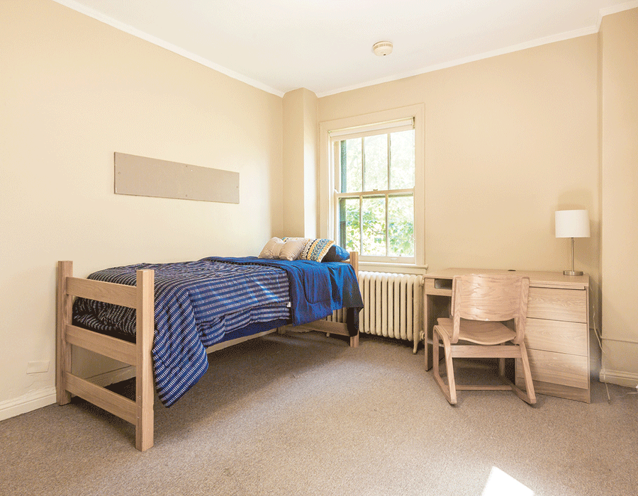 A bedroom with a single bed , desk and chair