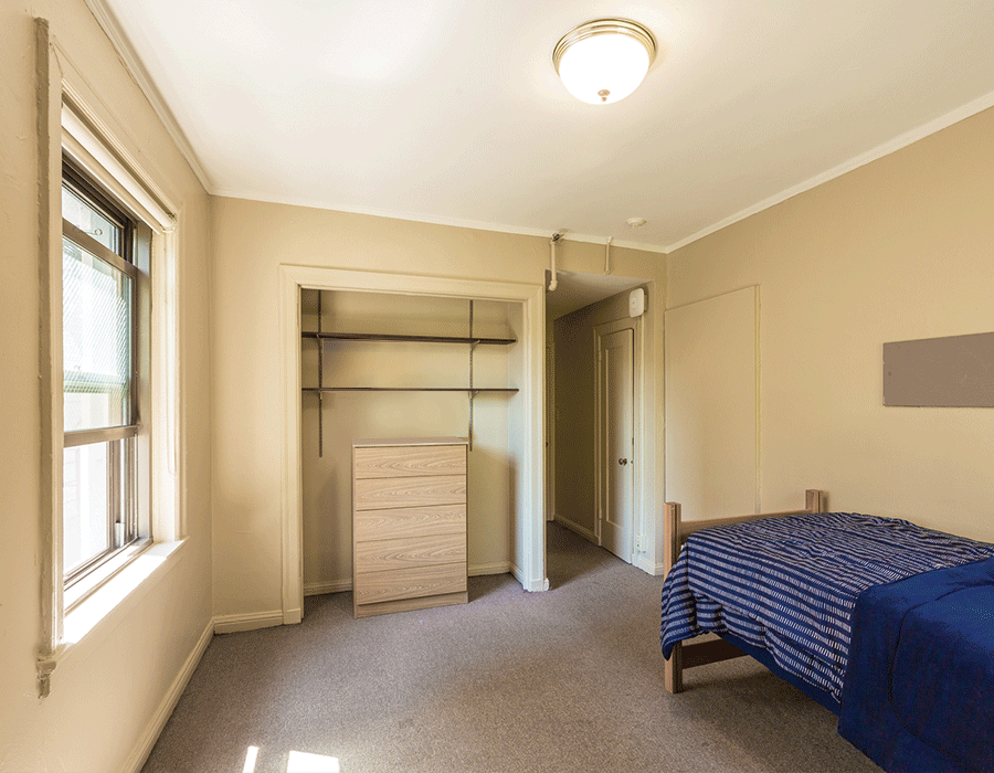 A bedroom with a bed a dresser and a window