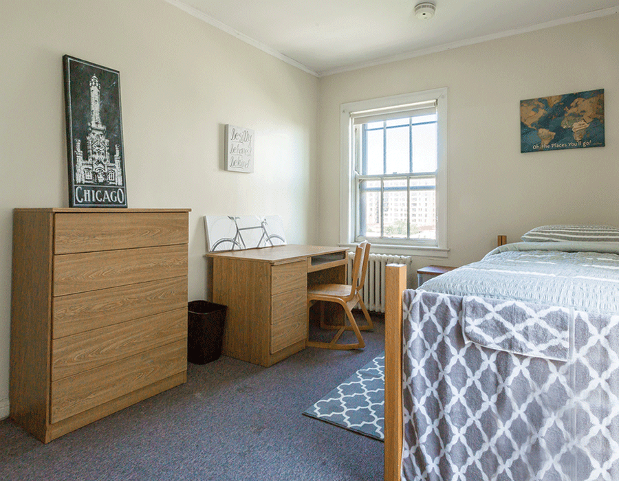 A bedroom with a bed , desk , dresser and chair.
