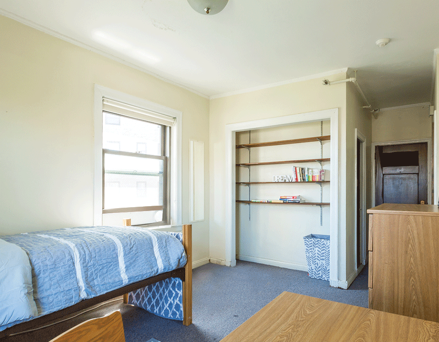 A bedroom with a bed , desk , shelves and a window.