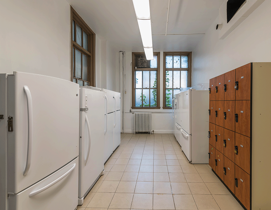 A kitchen with a lot of white refrigerators and lockers