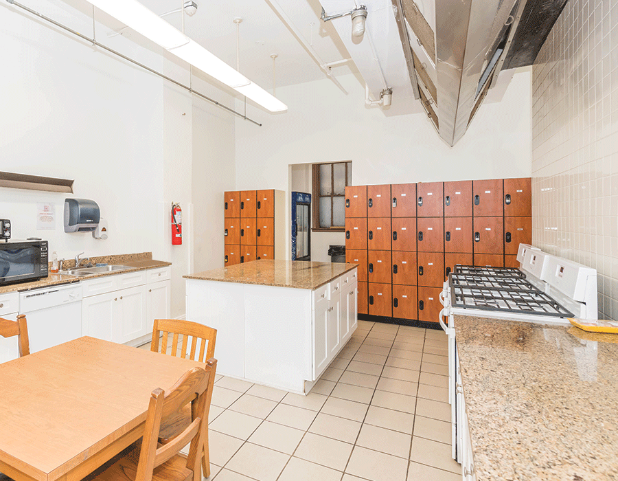A kitchen with a table and chairs and lots of lockers