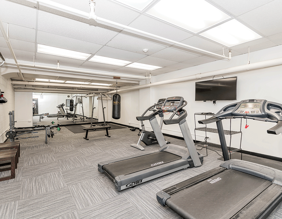 A gym with treadmills and a television on the wall.